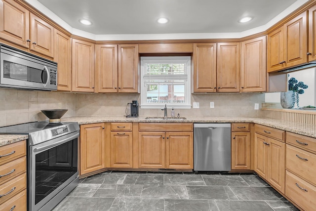kitchen featuring appliances with stainless steel finishes, tasteful backsplash, a sink, and light stone counters