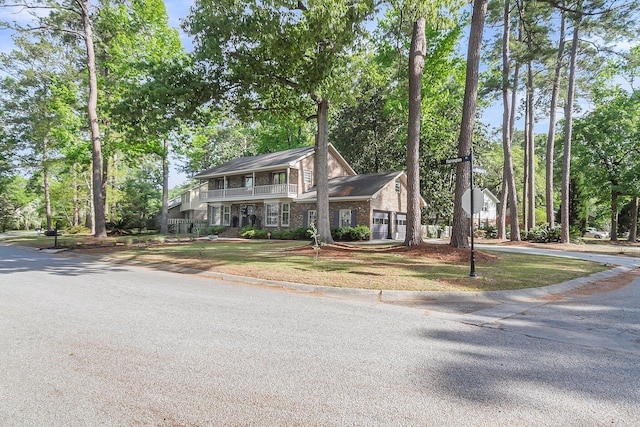 colonial inspired home featuring driveway, brick siding, and a balcony