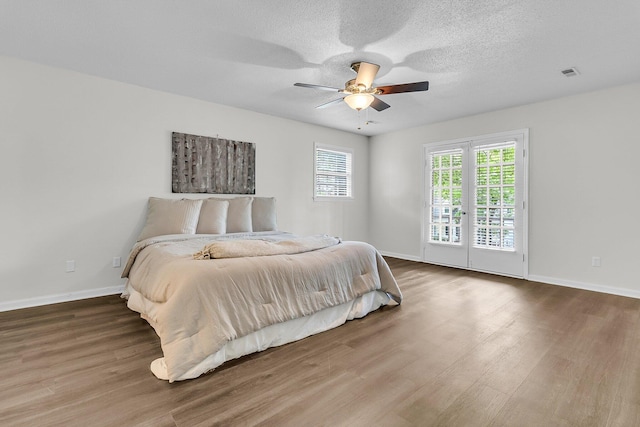 bedroom with baseboards, a ceiling fan, wood finished floors, and visible vents