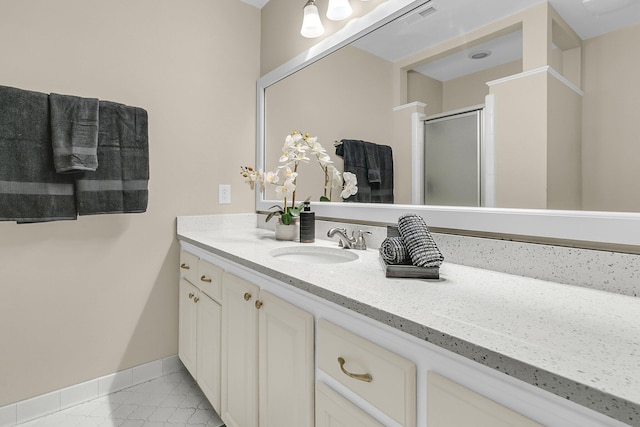full bath with double vanity, marble finish floor, baseboards, a sink, and a stall shower