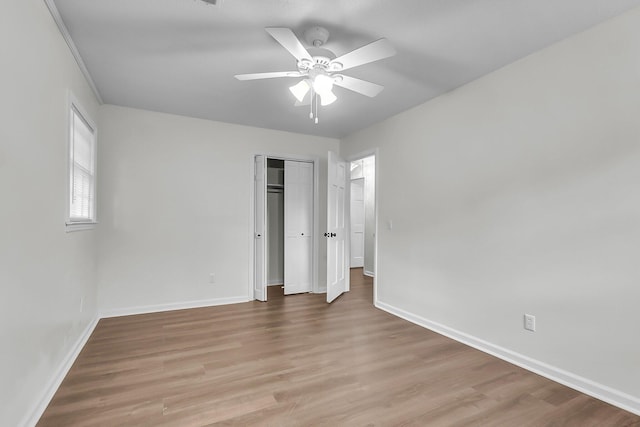 unfurnished bedroom featuring baseboards, ceiling fan, wood finished floors, and a closet