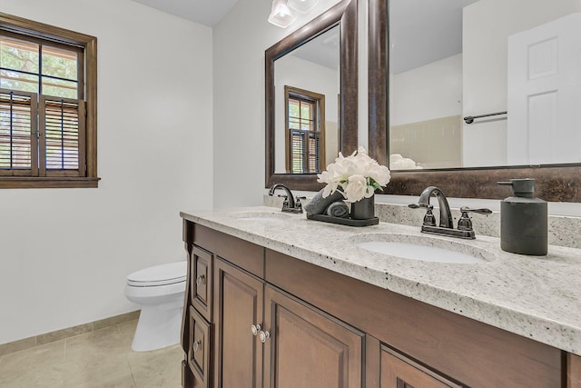 bathroom with a sink, tile patterned floors, baseboards, and toilet