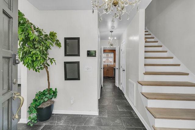 interior space with an inviting chandelier, marble finish floor, baseboards, and stairs