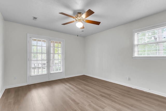 spare room featuring baseboards, ceiling fan, a healthy amount of sunlight, and wood finished floors