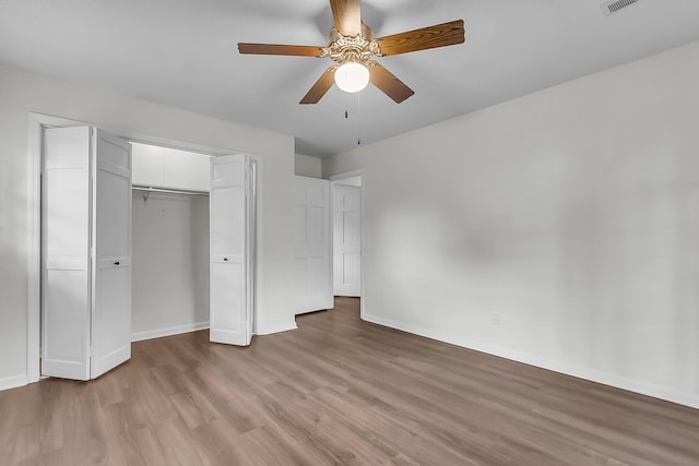 unfurnished bedroom with baseboards, ceiling fan, wood finished floors, and a closet