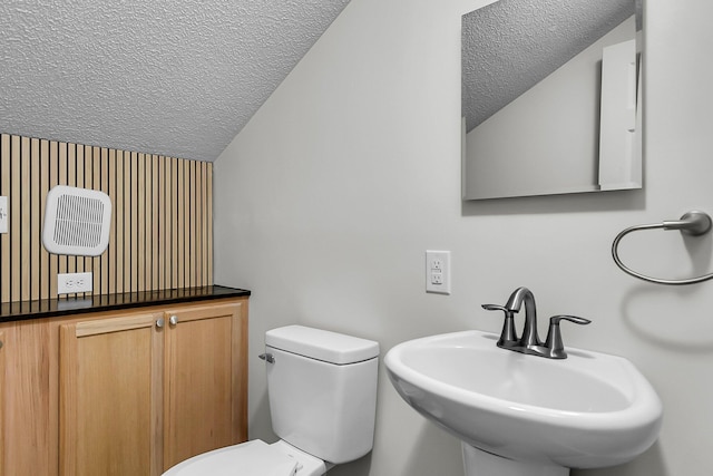 half bathroom with a sink, toilet, and a textured ceiling