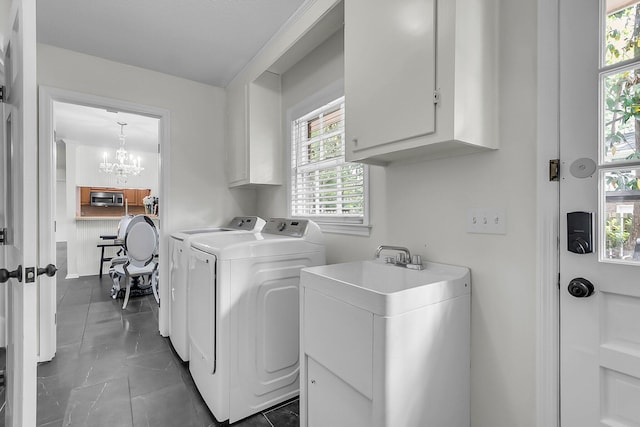 clothes washing area with a sink, an inviting chandelier, cabinet space, and washing machine and clothes dryer