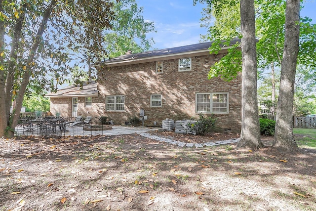 rear view of property with central air condition unit, crawl space, brick siding, and a patio area