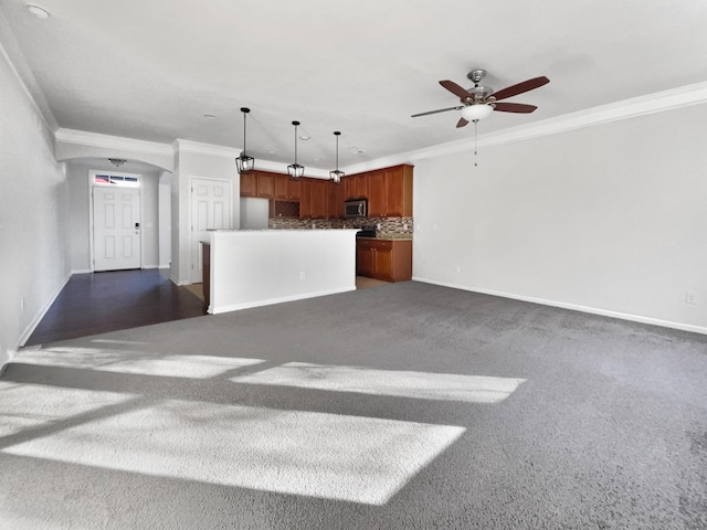 unfurnished living room featuring dark colored carpet, ceiling fan, and ornamental molding