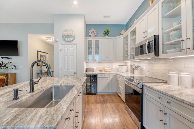 422 Cabrill Dr, Charleston, SC 29414 - kitchen featuring stainless steel appliances, a sink, white cabinets, light stone counters, and tasteful backsplash