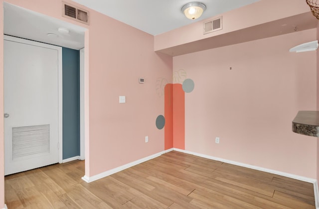 unfurnished room with visible vents, light wood-type flooring, and baseboards