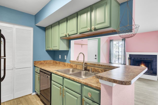 kitchen featuring green cabinetry, light wood-type flooring, black dishwasher, and a sink