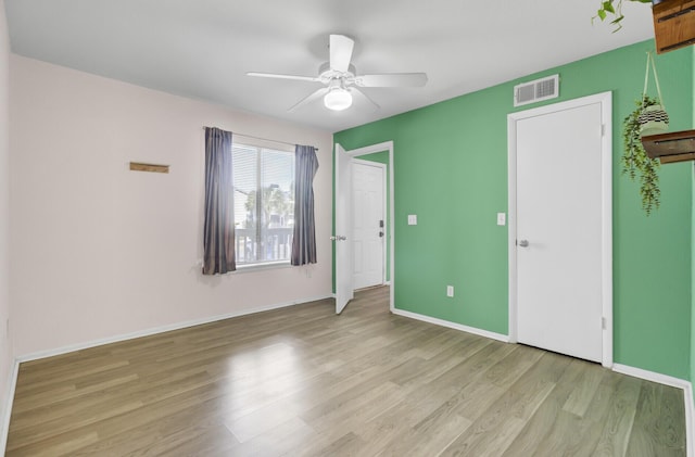 unfurnished room featuring baseboards, visible vents, a ceiling fan, and light wood-style floors