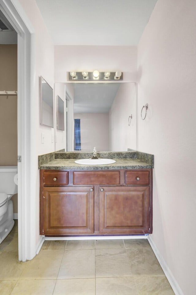 bathroom featuring tile patterned floors, baseboards, toilet, and vanity