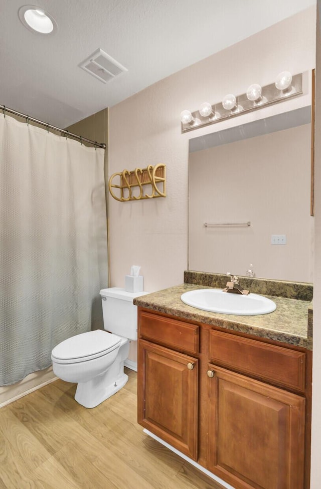 full bathroom with visible vents, toilet, a shower with shower curtain, wood finished floors, and vanity