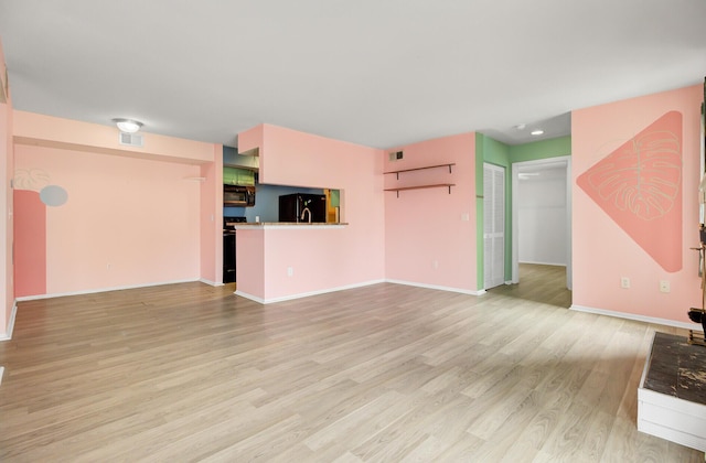 unfurnished living room featuring light wood finished floors, visible vents, and baseboards