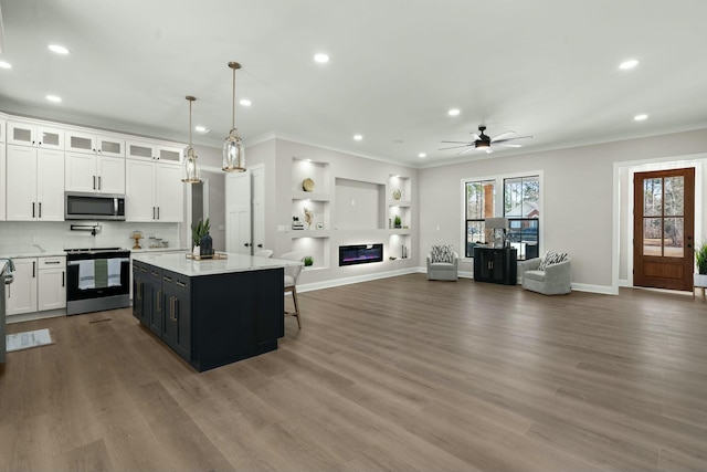 kitchen featuring a kitchen island, appliances with stainless steel finishes, open floor plan, decorative light fixtures, and light countertops