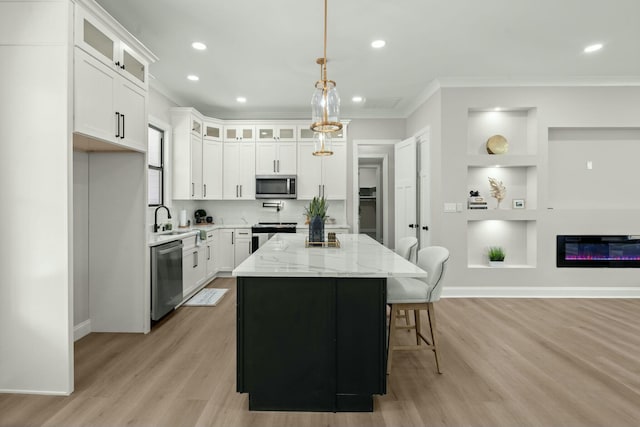 kitchen with glass insert cabinets, appliances with stainless steel finishes, a center island, light stone countertops, and white cabinetry