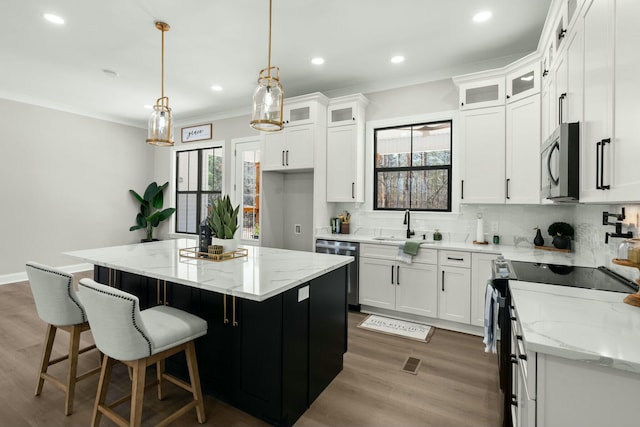 kitchen with white cabinets, glass insert cabinets, a center island, hanging light fixtures, and stainless steel appliances