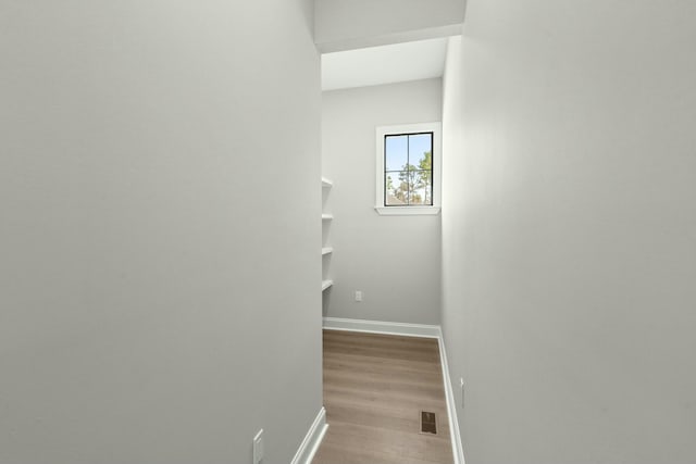 corridor featuring light wood-type flooring, visible vents, and baseboards