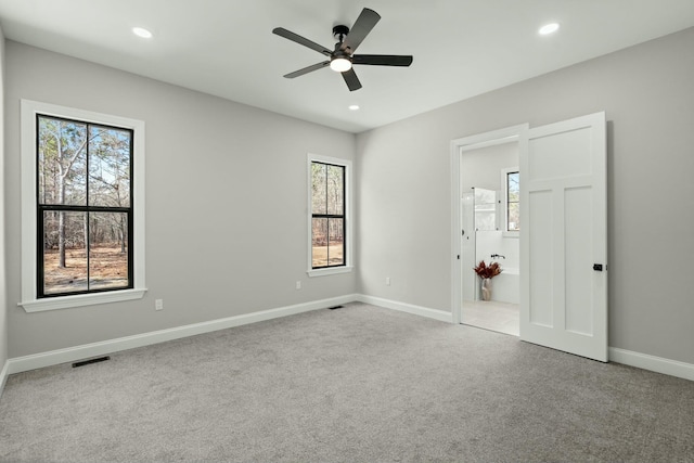 spare room featuring light carpet, plenty of natural light, baseboards, and recessed lighting