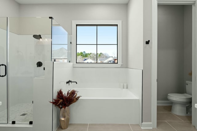 bathroom with a stall shower, a garden tub, toilet, and tile patterned floors