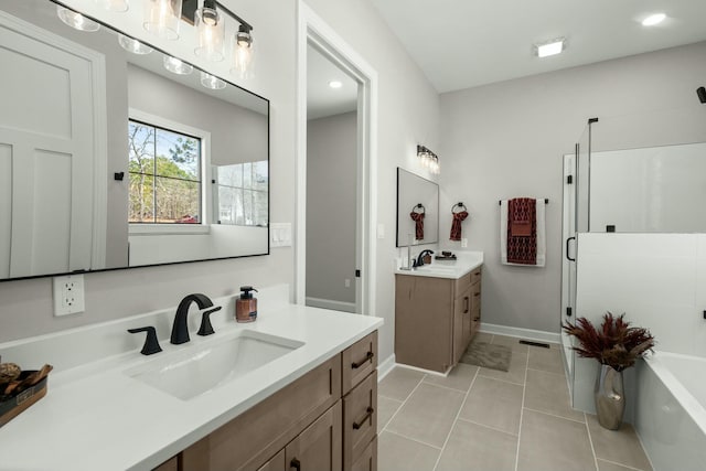 bathroom featuring a stall shower, a soaking tub, tile patterned floors, a sink, and two vanities