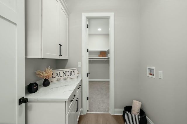 interior space featuring dark wood-style flooring, washer hookup, cabinet space, and baseboards