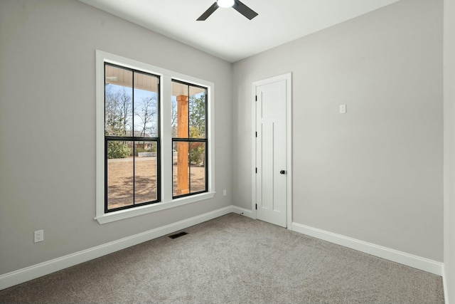 empty room featuring carpet floors, plenty of natural light, visible vents, and baseboards