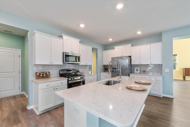 kitchen featuring white cabinets, stainless steel appliances, dark wood-type flooring, and a center island with sink