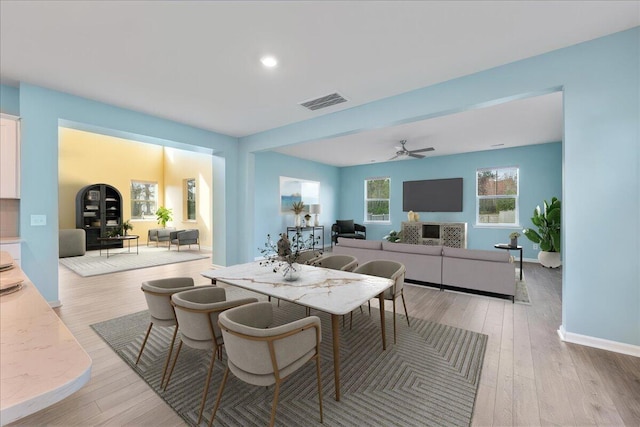 dining space with ceiling fan and light wood-type flooring