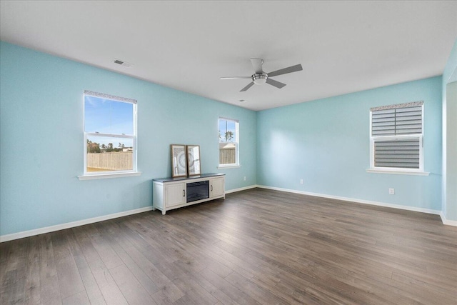 unfurnished living room featuring dark hardwood / wood-style floors, a wealth of natural light, and ceiling fan