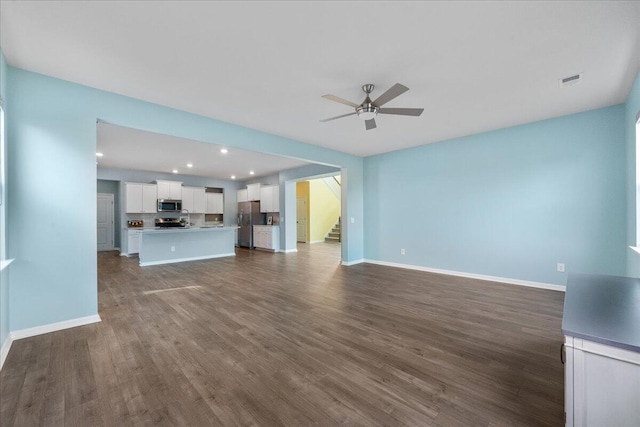 unfurnished living room featuring ceiling fan and dark wood-type flooring