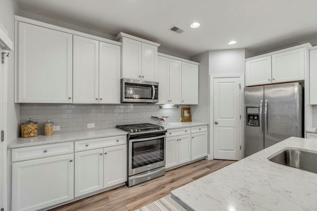 kitchen featuring white cabinets, tasteful backsplash, and appliances with stainless steel finishes