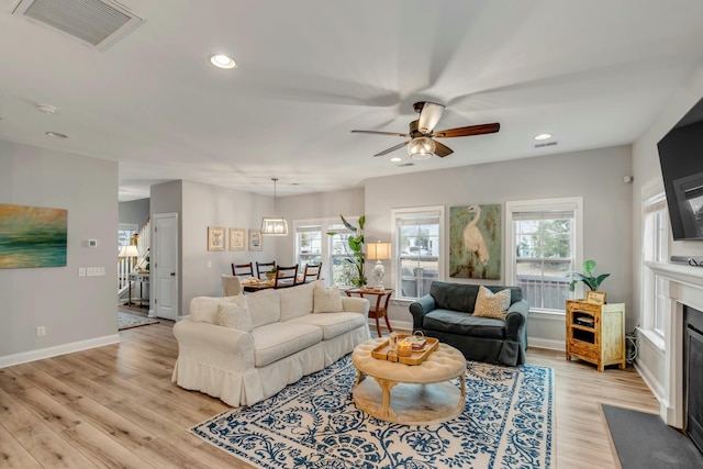 living room featuring ceiling fan, a healthy amount of sunlight, and light wood-type flooring