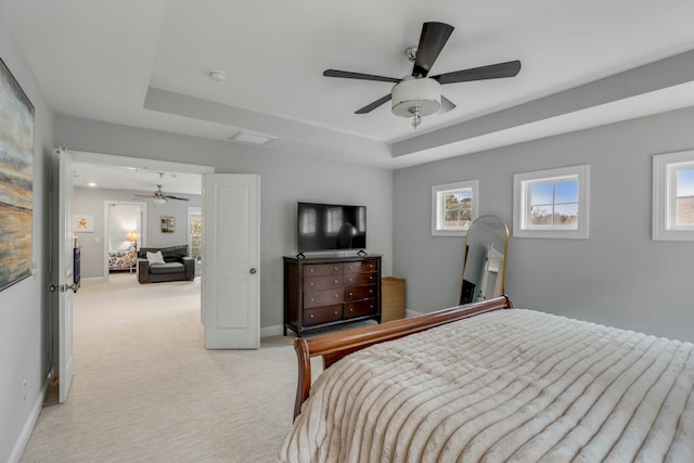 bedroom featuring ceiling fan, a raised ceiling, and light carpet