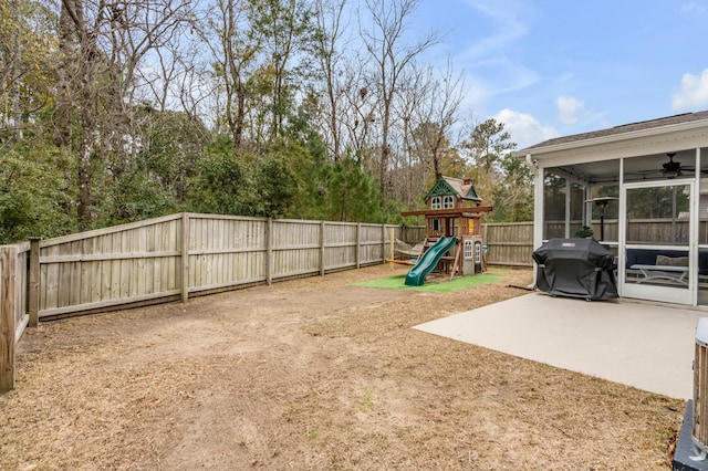 view of yard with a sunroom, a patio, a playground, and ceiling fan