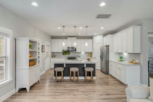 kitchen with pendant lighting, white cabinetry, and appliances with stainless steel finishes