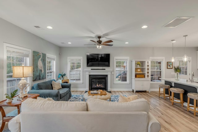 living room featuring sink, ceiling fan, and light hardwood / wood-style floors