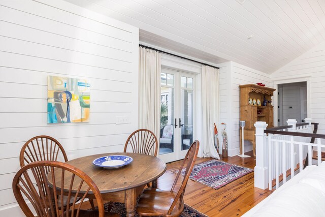 dining area with wood walls, french doors, wood ceiling, vaulted ceiling, and hardwood / wood-style flooring