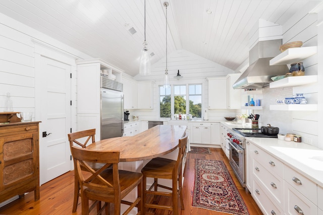 kitchen featuring white cabinetry, decorative light fixtures, vaulted ceiling, and high end appliances