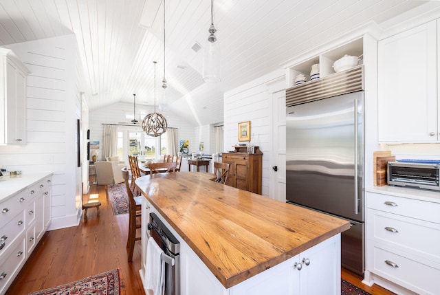 kitchen featuring lofted ceiling, hanging light fixtures, white cabinetry, built in fridge, and a center island