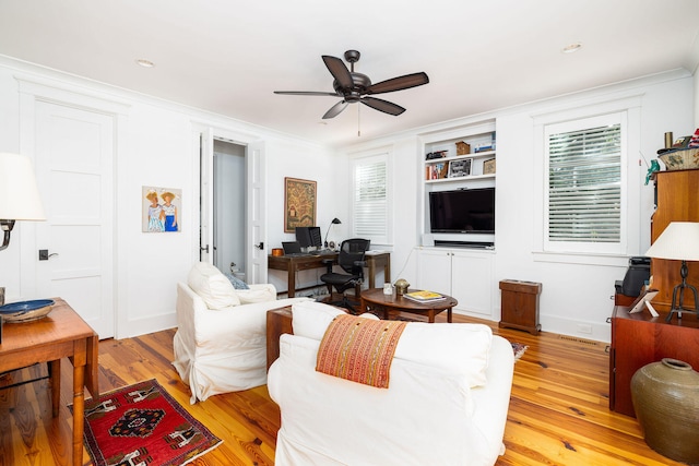 living room featuring crown molding, light wood-type flooring, and ceiling fan