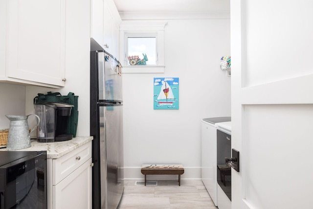 kitchen featuring white cabinets, beverage cooler, washer and dryer, stainless steel refrigerator, and light stone counters