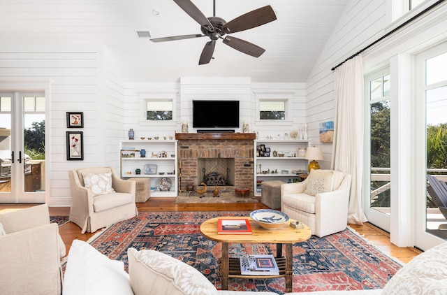 living room featuring light hardwood / wood-style flooring, a brick fireplace, high vaulted ceiling, and ceiling fan