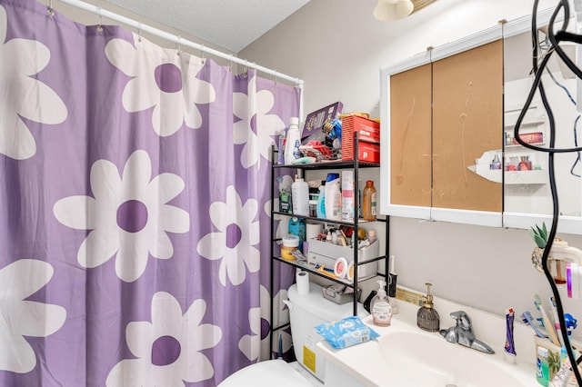 bathroom featuring curtained shower, a textured ceiling, toilet, and vanity