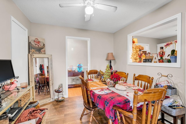 dining room featuring a ceiling fan, a textured ceiling, and wood finished floors