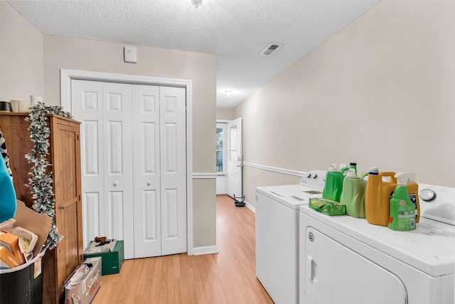 clothes washing area featuring laundry area, visible vents, washer and clothes dryer, and light wood-style floors