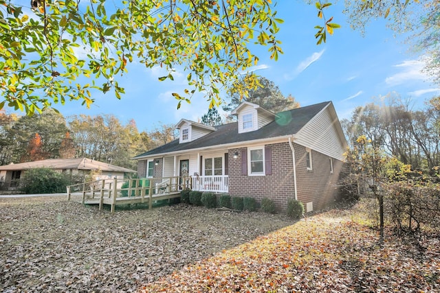 cape cod-style house with covered porch and brick siding