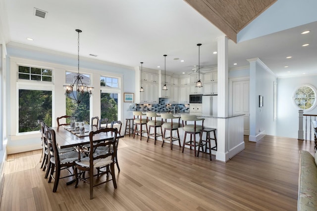 dining room with a chandelier, visible vents, light wood-style flooring, and ornamental molding